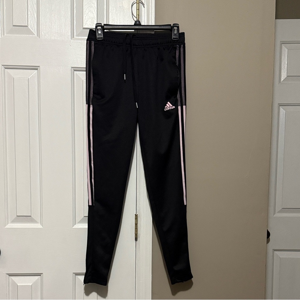 Women’s Black Adidas Tiro track pants with pink stripes.